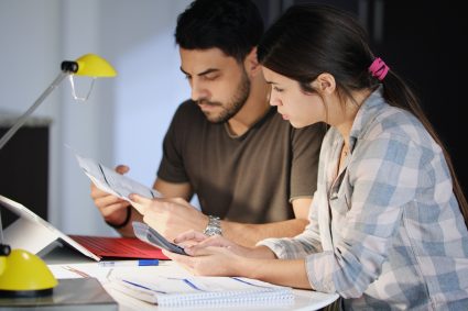 Young couple reviewing invoices and doing family business plan. Concept of money and economic problem for man and woman living together