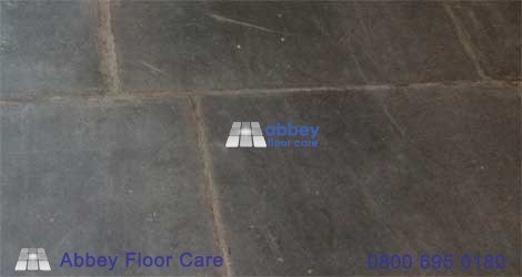 Open grout gaps being repaired between old Welsh slate floor tiles