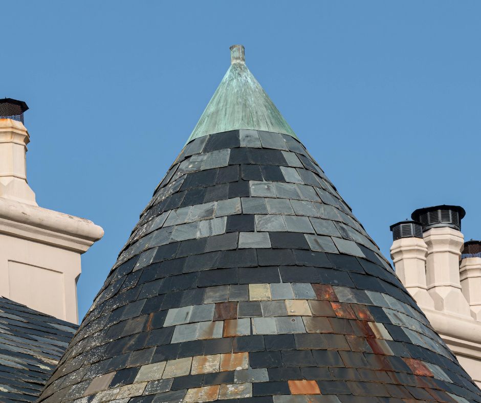 Conical slate turret roof topped with a copper finial on a heritage structure
